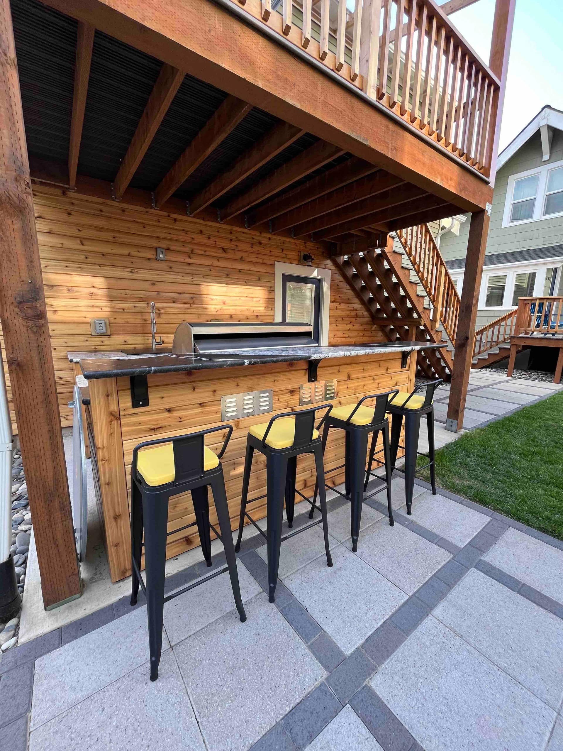 Outdoor kitchen and bar seating under a shade umbrella